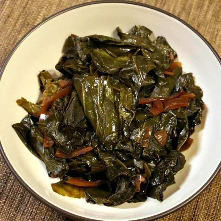 Bowl of sautéed collard greens with thin red pepper strips.