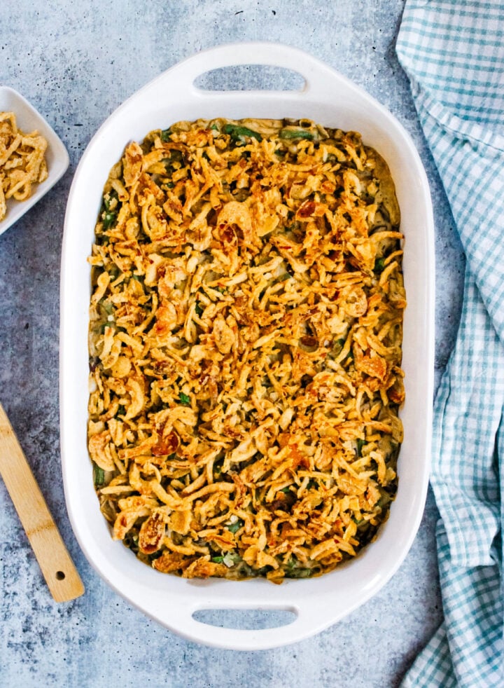 Vegan green bean casserole in a white baking dish, topped with lots of crispy fried onions.