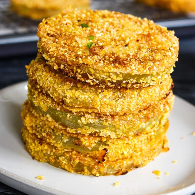 Stack of crispy onion rings with a crunchy crushed-nut coating on a white plate, stacked high.