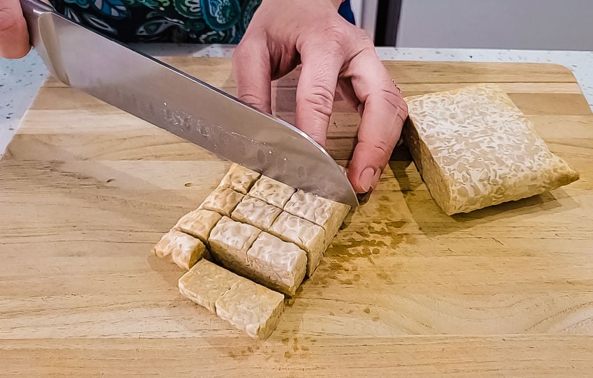 Cutting tempeh into bite-sized pieces for stir fry