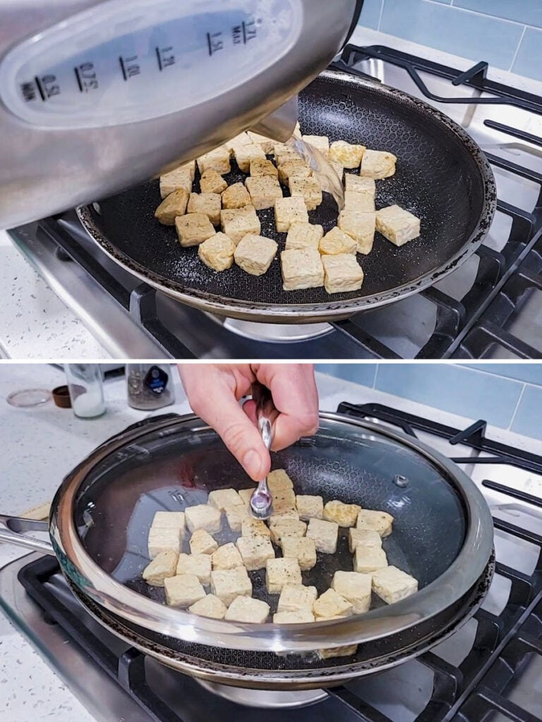 Tempeh cubes frying in a seasoned nonstick skillet on a gas stove while water is poured into the pan from a kettle.